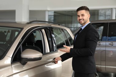 Galerideki yeni arabanın yanındaki genç satıcı.