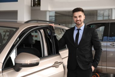 Galerideki yeni arabanın yanındaki genç satıcı.