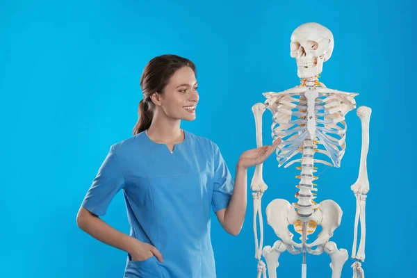 Ortopedista Feminina Com Modelo Esqueleto Humano Fundo Azul — Fotografia de Stock