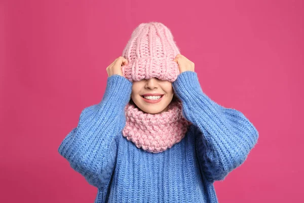 暖かいセーター 雪と深紅の背景に帽子を身に着けている若い女性 冬の季節 — ストック写真