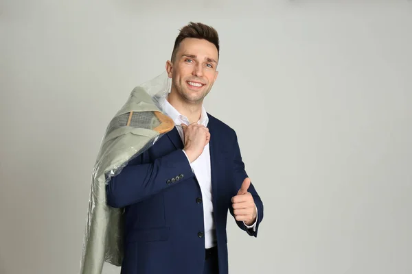 Hombre Sosteniendo Percha Con Chaqueta Bolsa Plástico Sobre Fondo Gris —  Fotos de Stock