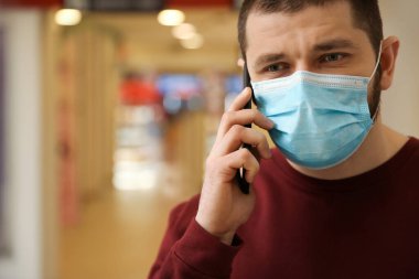 Tek kullanımlık maskeli bir adam içeride telefonla konuşuyor. Tehlikeli bir virüs.