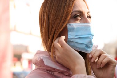 Şehir caddesinde tıbbi maskeli bir kadın. Virüs koruması