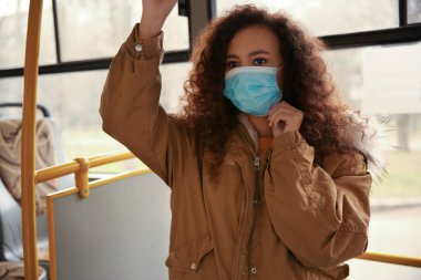 Otobüste tek kullanımlık maskeli Afro-Amerikalı kadın. Virüs koruması