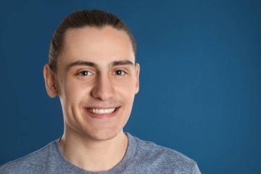 Mavi arka planda mutlu genç adamın portresi, metin için boşluk