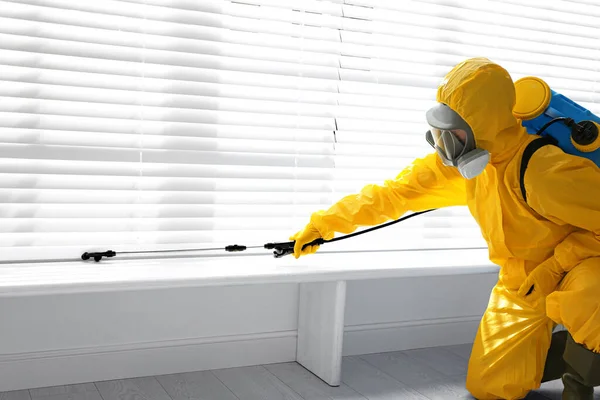 窓に殺虫剤を噴霧保護スーツの男性労働者は屋内でまだ 害虫駆除 — ストック写真