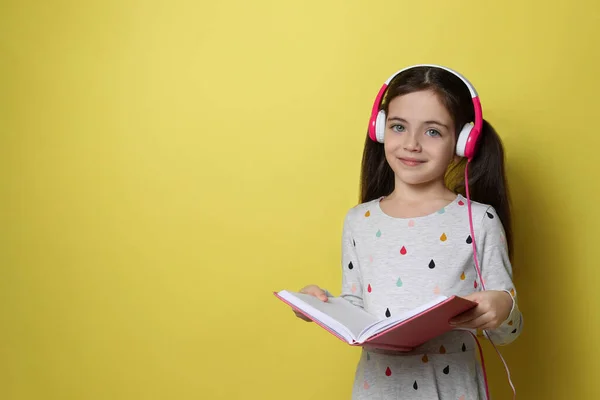 Słodka Dziewczynka Słuchawkami Słuchającymi Audiobooka Żółtym Tle Miejsce Tekst — Zdjęcie stockowe