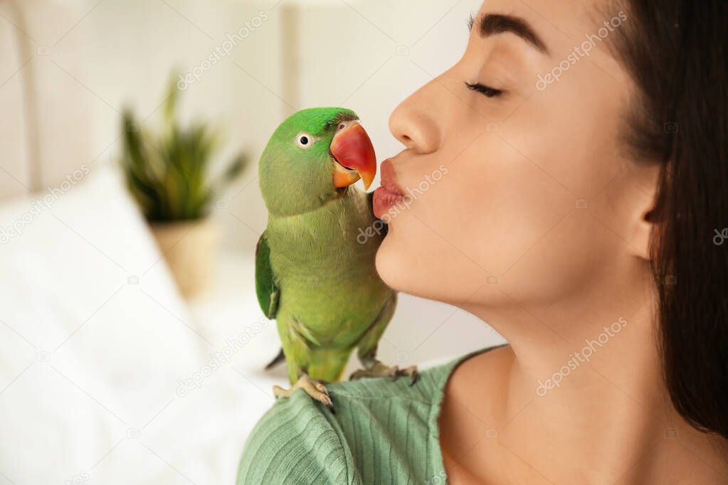 Young woman with Alexandrine parakeet indoors, closeup. Cute pet