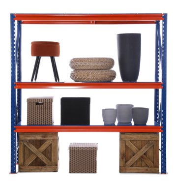 Ahşap sandıklar ve beyaz arka planda farklı ev eşyaları olan parlak metal raf ünitesi.