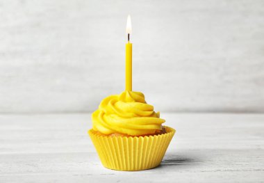 Beyaz ahşap masada kremalı ve yanan mumlu nefis bir doğum günü pastası.