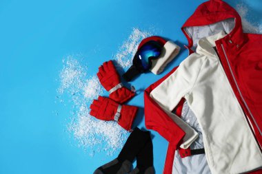 Açık mavi arka planda şık kış sporu giysileri, düz yatış