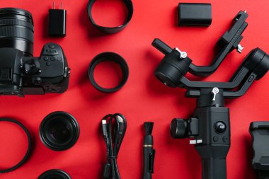 Flat lay composition with camera and video production equipment on red background clipart