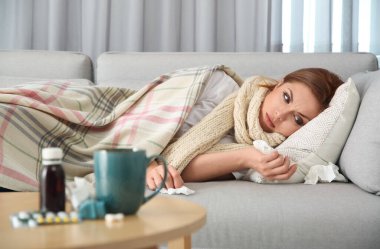 Hasta kadın evdeki kanepede yatıyor. Grip virüsü