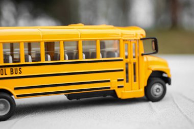 Sarı oyuncak okul otobüsü arka planda bulanık, yakın plan. Öğrenciler için taşıma
