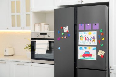 Çocuk resimleri, notlar ve mıknatıslarla dolu modern buzdolabı. Metin için boşluk