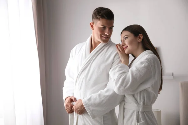 Pareja Feliz Usando Albornoces Cerca Ventana Habitación —  Fotos de Stock