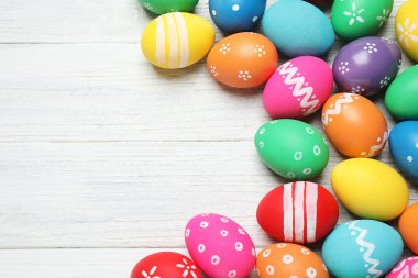 Beyaz ahşap zemin üzerinde bir sürü parlak Paskalya yumurtası, düz yatıyordu. Metin için boşluk