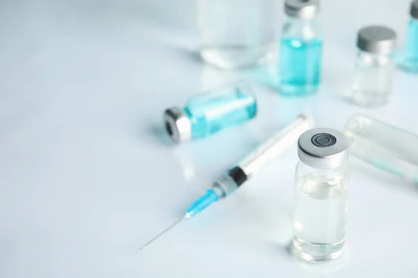 Vials and syringe on light table. Vaccination and immunization