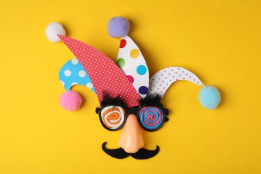 Funny face made of party items on yellow background, flat lay. April Fool's Day clipart