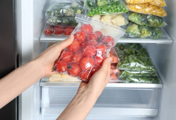 Mulher Segurando Saco Plástico Com Tomates Congelados Perto Refrigerador Aberto — Fotografia de Stock