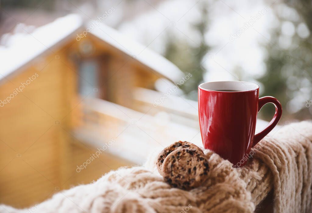 Fresh coffee, tasty cookies and knitted fabric outdoors on winter morning. Space for text
