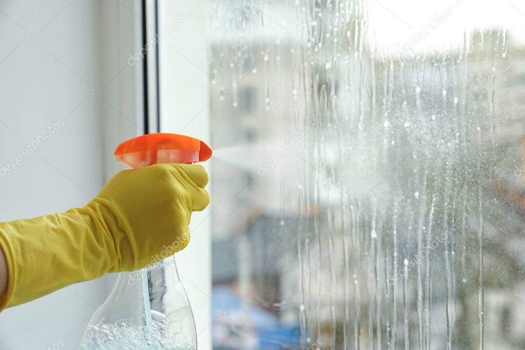 Woman cleaning window at home, closeup. Space for text