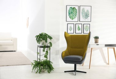 Rahat koltuk ve tropikal yaprak resimleriyle süslü bir oda.