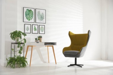 Rahat koltuk ve tropikal yaprak resimleriyle süslü bir oda.