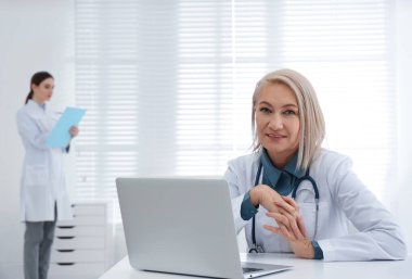 İş yerinde beyaz önlüklü olgun kadın doktor portresi.