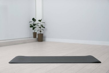 Odanın zemininde siyah yoga minderi açık.