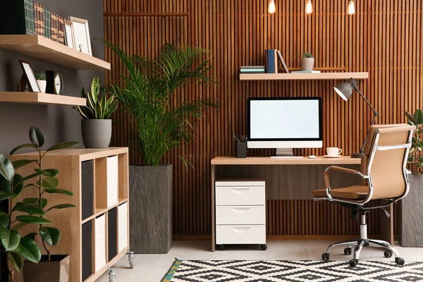 スタイリッシュな部屋のインテリアで木製の壁の近くにコンピュータと快適な職場 ホームオフィスデザイン — ストック写真