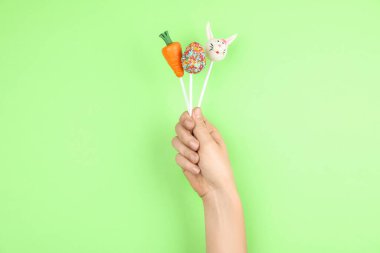 Açık yeşil arka planda leziz pastaları olan bir kadın, yakın plan. Paskalya tatili