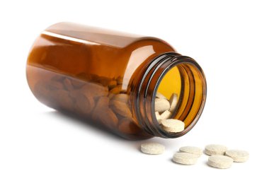 Beyaza izole edilmiş vitamin haplarıyla dolu şişe.