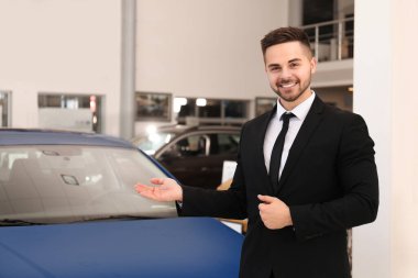 Galerideki yeni arabanın yanındaki genç satıcı.