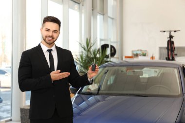 Araba galerisinde anahtarı olan genç bir satıcı.
