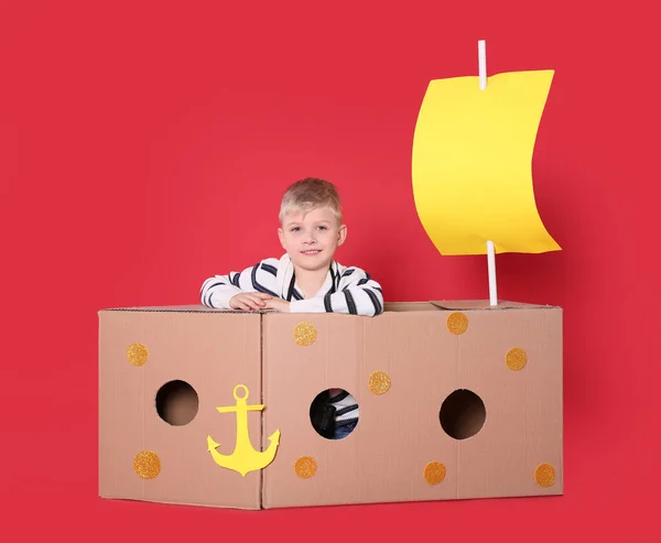 Kleines Kind Spielt Mit Schiff Aus Pappschachtel Auf Rotem Hintergrund — Stockfoto