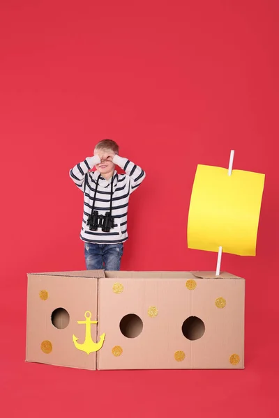 Malé Dítě Hrát Lodí Lepenkové Krabice Červeném Pozadí — Stock fotografie