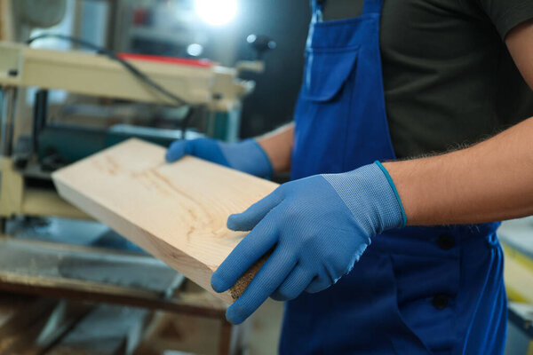 Professional carpenter with wooden board in workshop, closeup