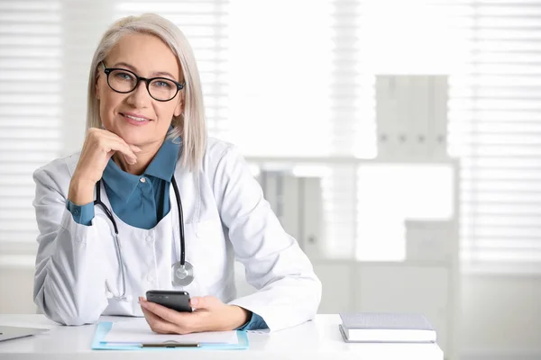 Gammal Kvinnlig Läkare Med Smartphone Vid Bordet Kontoret — Stockfoto