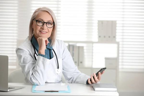 Gammal Kvinnlig Läkare Med Smartphone Vid Bordet Kontoret — Stockfoto