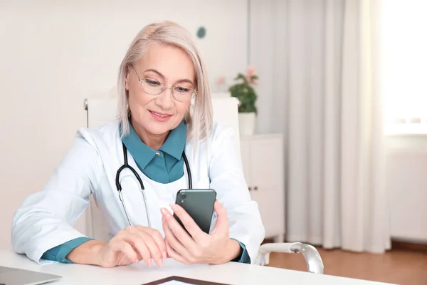 Gammal Kvinnlig Läkare Med Smartphone Vid Bordet Kontoret — Stockfoto