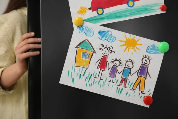 Woman opening refrigerator\'s door with drawings, closeup