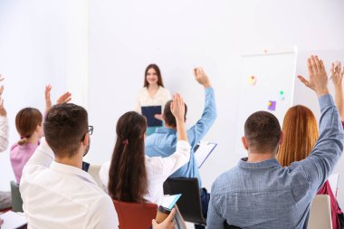 İnsanlar iş eğitiminde kapalı alanda soru sormak için el kaldırıyor.