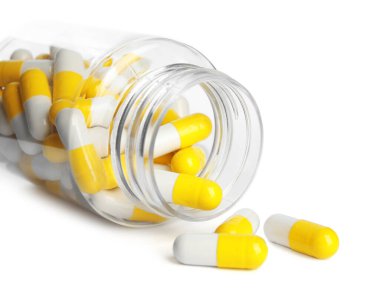 İçinde vitamin hapları olan şişe beyaza izole edilmiş, yakın plan.