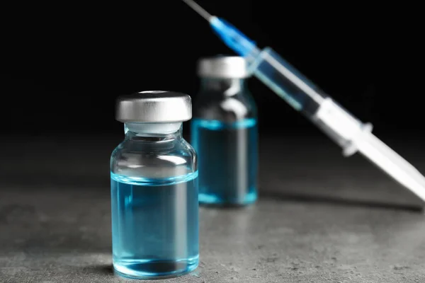瓶子和注射器在灰色桌子上疫苗和免疫接种 — 图库照片