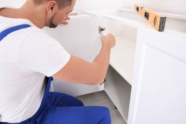 İşçi mutfağa dolap kapısı kuruyor