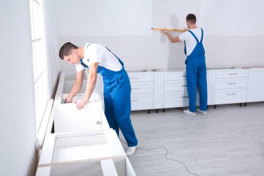 Bakım işçileri yeni mutfak mobilyalarını içeri kuruyor.