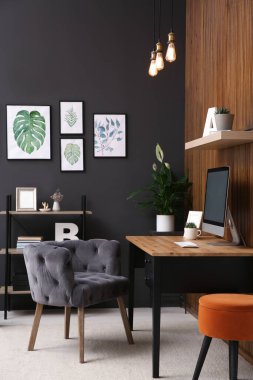 Odanın iç kısımlarında ahşap duvarın yanında bilgisayarı olan rahat bir iş yeri. İç ofis tasarımı