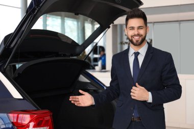 Galerideki yeni arabanın yanındaki genç satıcı.