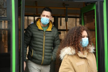 Tek kullanımlık maskeli insanlar otobüsten dışarı çıkıyorlar. Virüs koruması